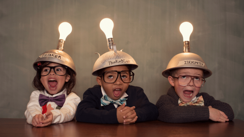 3 children being googy wearing helmets with lightbulbs on them to highlight the question, "What is Classroom Management?"