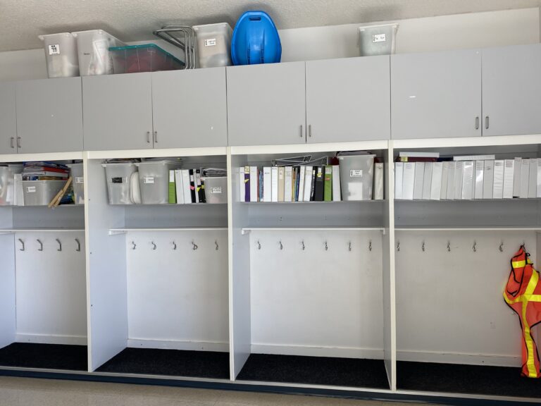 Classroom Cubbies with a row of white binders over them, and grey cupboard doors after that for how to decorate a classroom with neutrals.